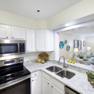 A modern kitchen with white cabinets, stainless steel appliances, and a granite countertop.