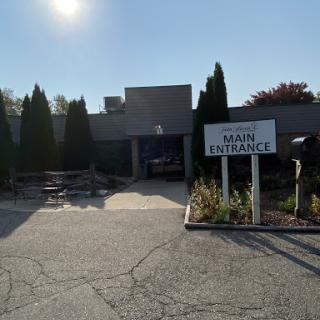 The main entrance of a building, featuring clear signage and well-maintained landscaping under bright sunlight.