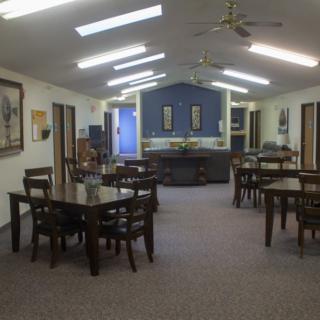 A spacious, well-lit meeting room with several tables and chairs arranged neatly.