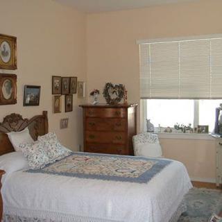 A cozy bedroom with vintage decor, featuring a wooden bed and dresser, adorned with framed wall art.