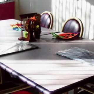 A sunlit dining area with a table set for a meal, including colorful utensils and neatly arranged place settings.