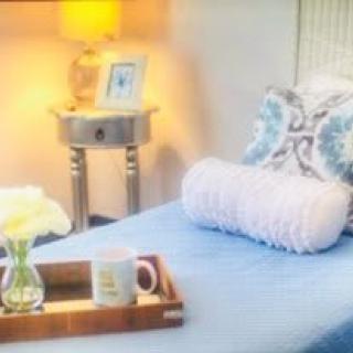 A cozy bedroom setup with a neatly made bed, decorative pillows, and a side table lamp.