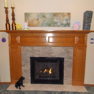 A cozy fireplace with a wooden mantel adorned with candles, a piece of artwork, and decorative items.