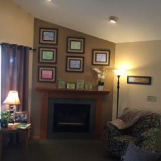 A cozy living room featuring a fireplace, framed pictures on the wall, and warm lighting from lamps.