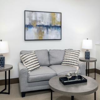 A modern living room with a gray sofa, abstract artwork, and matching lamps on side tables.