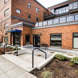 A modern brick building with glass windows and a landscaped entrance.