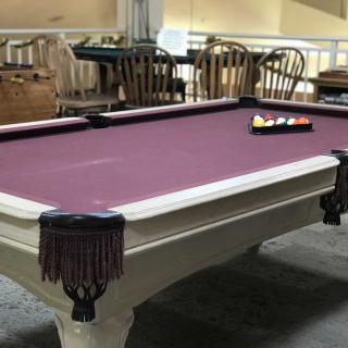 A pool table with a purple felt surface in an indoor setting.