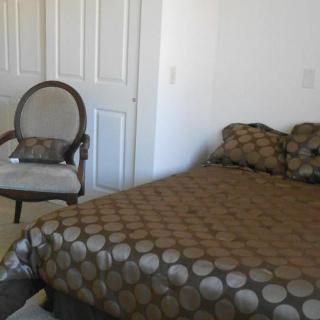 A cozy bedroom with a patterned bedspread and an upholstered chair.