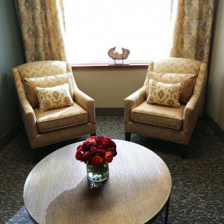 A cozy seating area with two armchairs and a round table adorned with a vase of flowers.