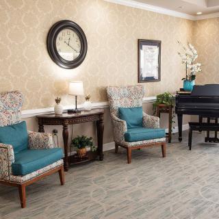 A cozy living room with two armchairs, a piano, and elegant decor.
