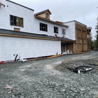 An unfinished house at a construction site with visible framework and building materials.