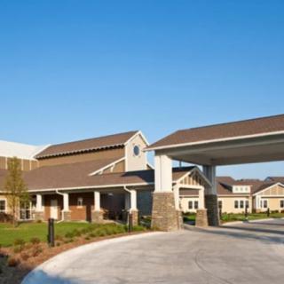 A modern building with a welcoming entrance and driveway under a clear blue sky.