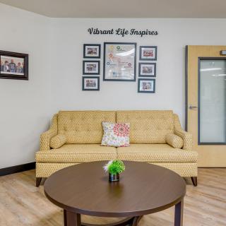 A cozy living room with a yellow sofa, wall art, and a round coffee table.