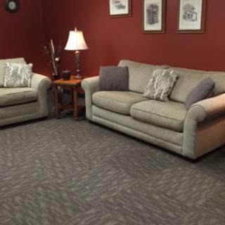 A cozy living room with two sofas, a table lamp, and wall art.