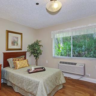 A cozy bedroom with a single bed and a large window offering garden views.