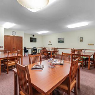 A well-lit dining area with wooden tables and chairs, suitable for communal gatherings.
