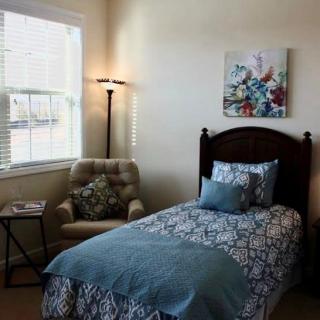 A cozy bedroom with a single bed and an armchair by the window.