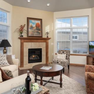 A cozy living room featuring a fireplace, comfortable seating, and large windows.
