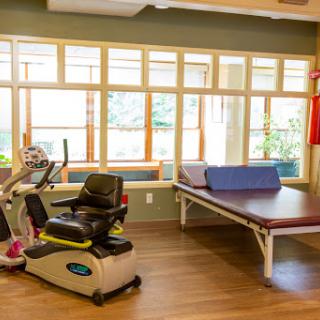 A bright and inviting therapy room equipped with exercise machines and a treatment table.