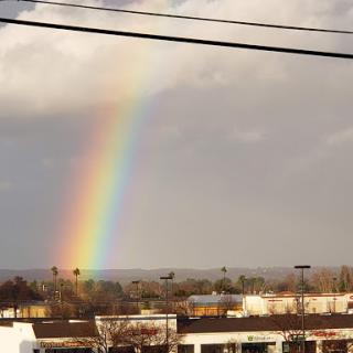 A beautiful rainbow arcs across the sky after a rain shower, showcasing nature's vibrant colors.