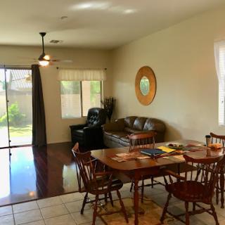 A cozy and inviting living and dining space featuring a wooden table, comfortable seating, and ample natural light.