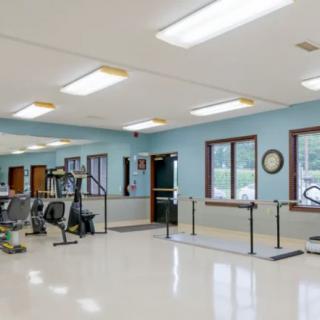 A spacious rehabilitation gym equipped with exercise machines and parallel bars.