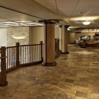 A hotel lobby featuring a reception desk with elegant lighting and tiled flooring.