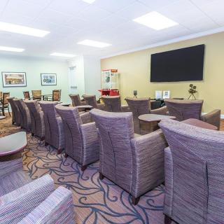 A modern meeting room setup with comfortable chairs and a large television screen.