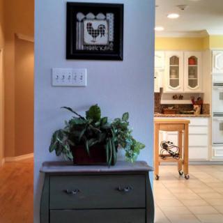 A cozy home interior with wall art and a plant near the kitchen.