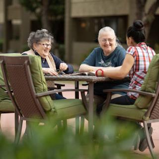 Three people enjoying a sunny day outdoors, engaged in a friendly conversation.