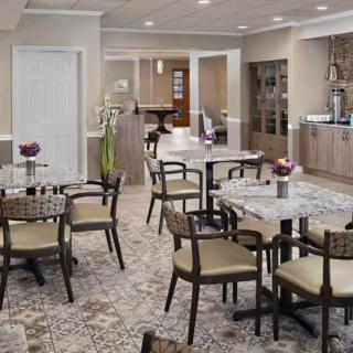 A modern dining area with tables and chairs arranged neatly, featuring stylish interior design and carpeted flooring.