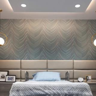 A modern bedroom featuring elegant wallpaper, pendant lighting, and a padded headboard in soothing blue tones.