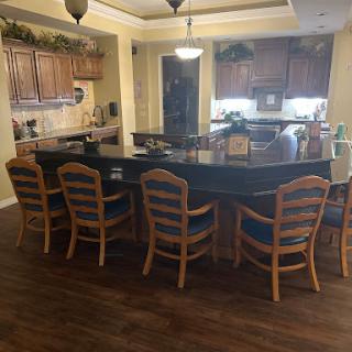A spacious and inviting kitchen featuring a large island with bar stools, wooden cabinets, and modern lighting.