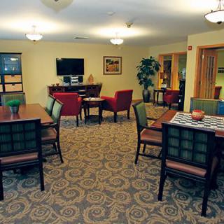 A cozy community living room with tables, chairs, and a television.