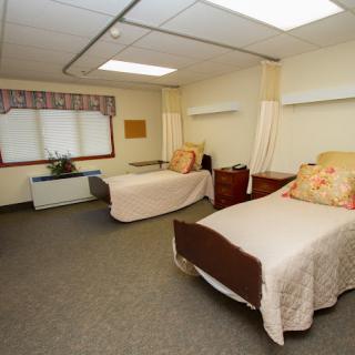 A cozy room with two single beds, nightstands, and a window adorned with curtains.