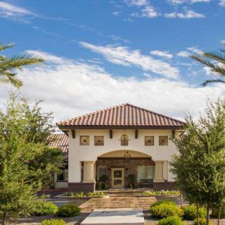 A beautiful house with a tiled roof, surrounded by lush greenery and clear blue sky.