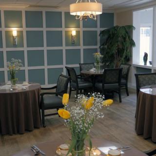 A cozy dining room with round tables, chairs, and floral decorations.
