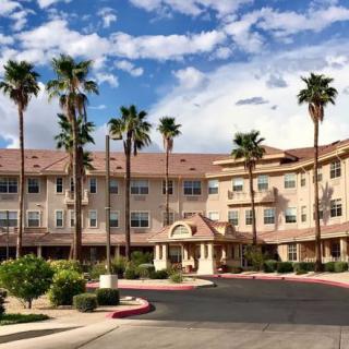 A large multi-story building surrounded by palm trees under a partly cloudy sky.