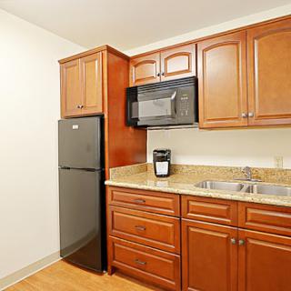A modern kitchen featuring wooden cabinets and essential appliances.