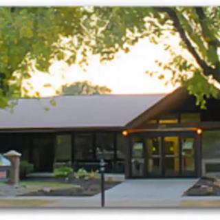A building surrounded by trees with a visible entrance and pathway at sunset.