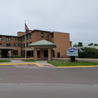 A hospital building with an American flag and a street sign, viewed from across the road.