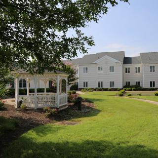 A serene outdoor area featuring a gazebo and a large lawn in front of a building.
