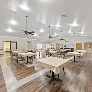 A spacious and well-lit dining area featuring neatly arranged tables and chairs, creating a welcoming atmosphere.
