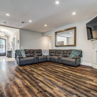 A modern living room featuring a large sectional sofa, hardwood floors, and a wall-mounted TV.