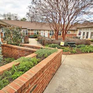A peaceful courtyard with brick walls, landscaping, and walkways.