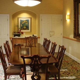 Elegant dining room with a long table and wooden chairs, adorned with artwork and a warm lighting ambiance.