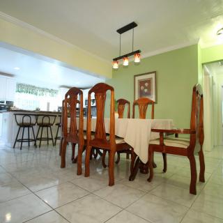 A cozy dining room with a wooden table and chairs, illuminated by a modern chandelier.