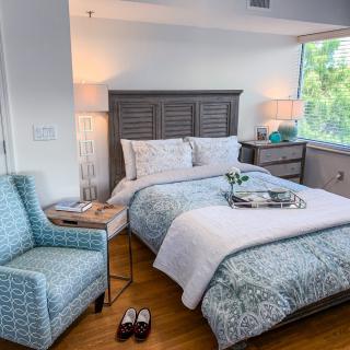 A cozy bedroom with a neatly made bed, decorative pillows, and a bedside table with lamps.