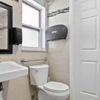 A modern bathroom with a sink, toilet, and towel dispenser.