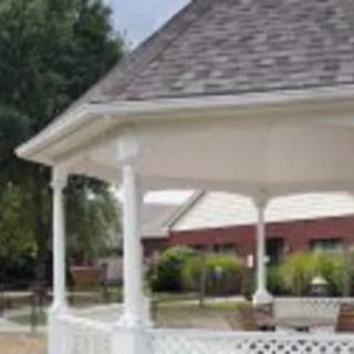 A white gazebo situated in a garden or park setting.